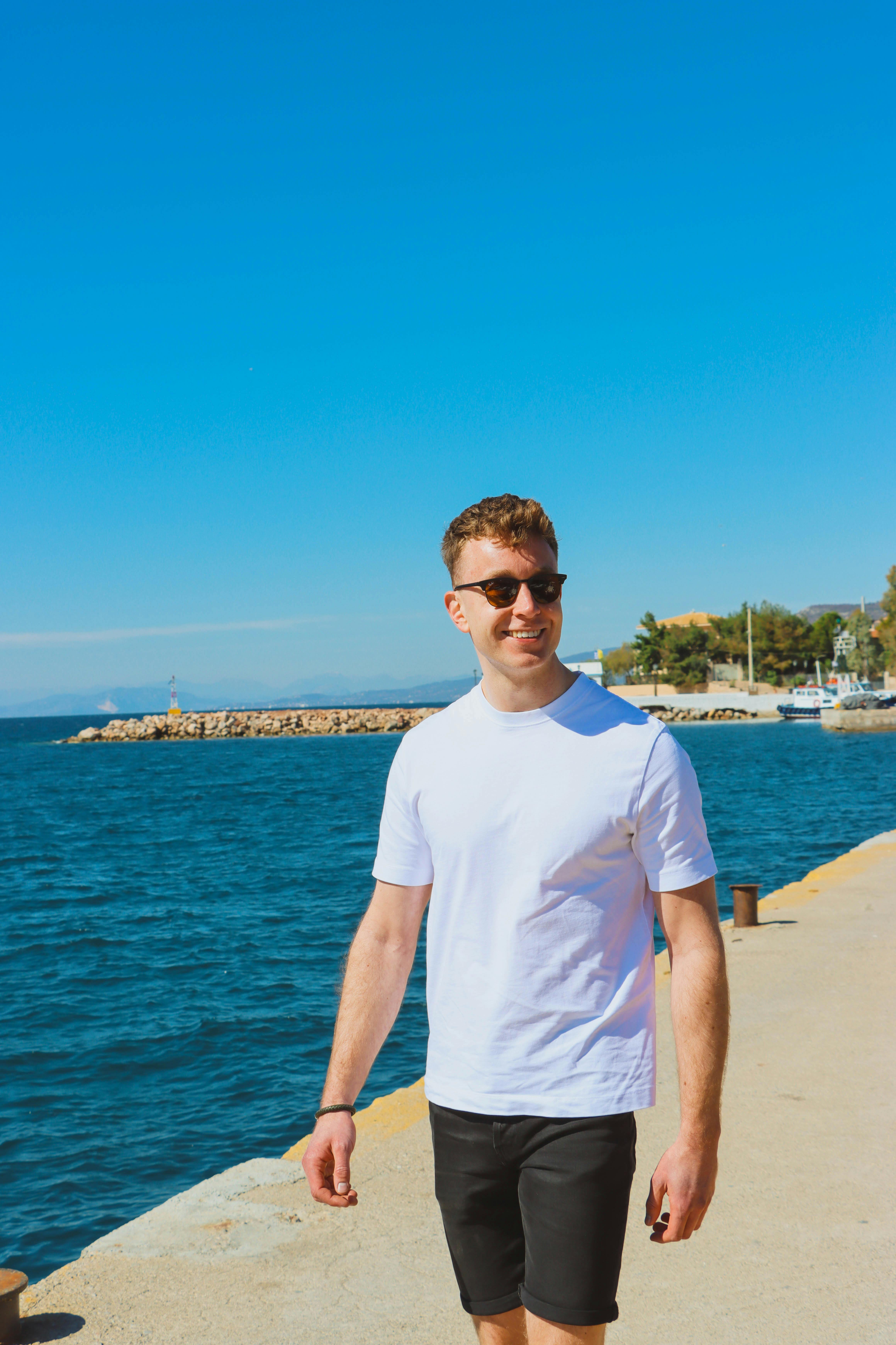 man lachend met zonnebril op loopt langs de kust in Griekenland