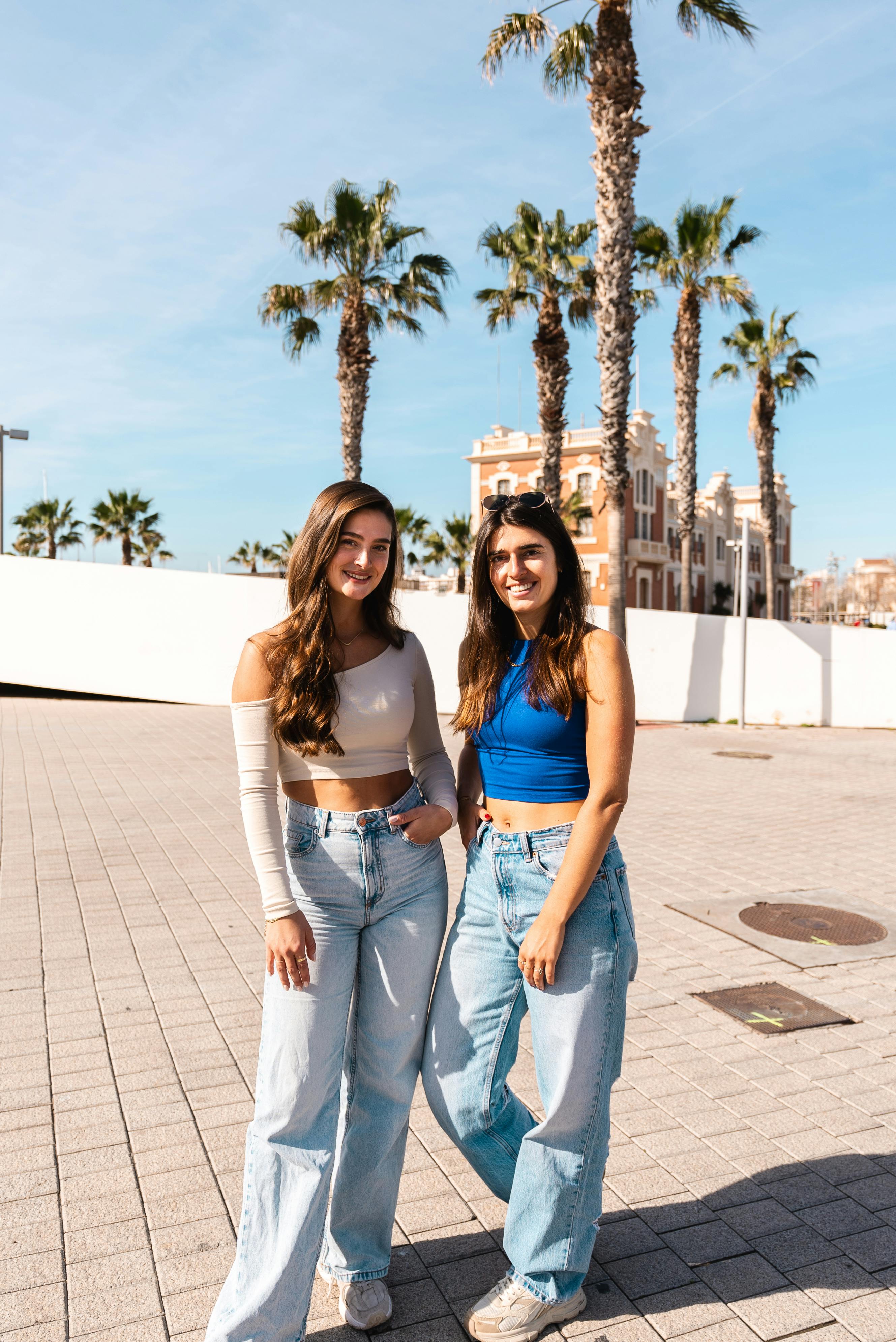 Twee vrouwen lachend met palmbomen op de achtergrond